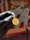 Original photo of the 24K Anime Inspired Double Sided Pendant held in a black glove