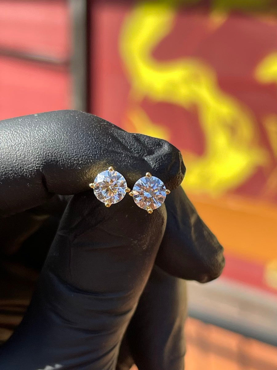 Diamond stud earrings displayed by hand at TA Jewelers