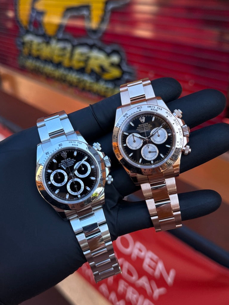 Two luxury watches displayed by hand at TA Jewelers
